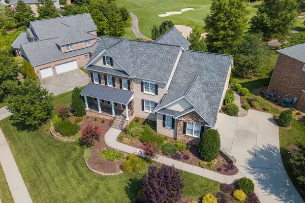 Aerial view of a landscaped home with planting beds, lawn, and a curving front walkway